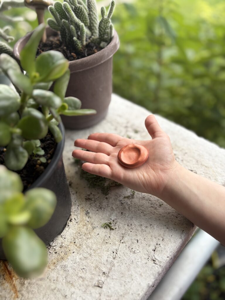 What a Worry Stone Is (And Why We Make Them by Hand) Shows a sherwood and sage handmade worry stone in the palm of the hand