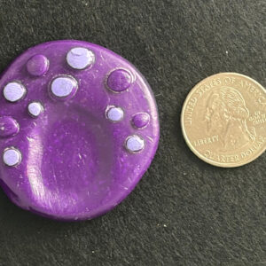 Handmade purple textured polymer clay worry stone next to a US quarter for scale